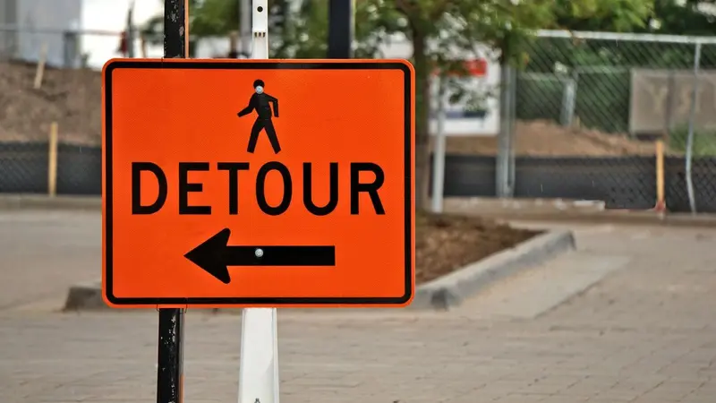 Orange detour sign with an arrow pointing left