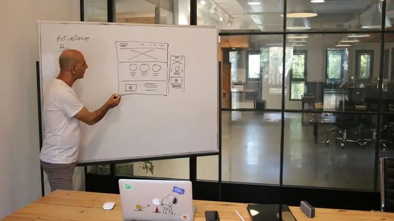Man drawing a diagram on a whiteboard in an office