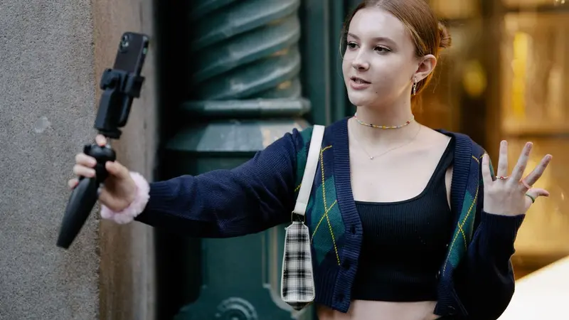 Young woman holding a selfie stick while recording a video