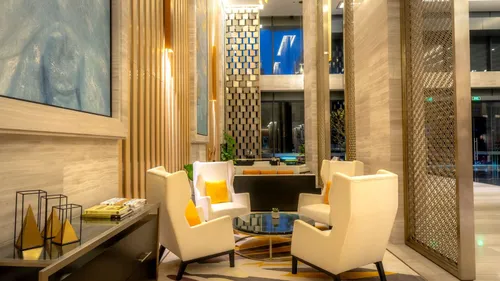Elegant hotel lounge with cream armchairs, gold accents and warm lighting