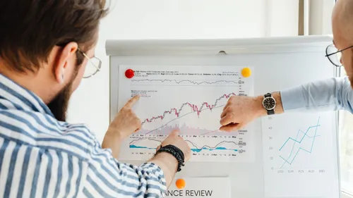 Colleagues presenting performance charts on a whiteboard during a marketing team review