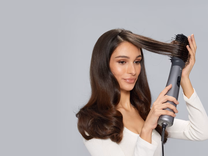 تصفيف الشعر باستخدام جهاز تصفيف الشعر Braun Air Styler باللون الرمادي، للحصول على تجعيدات ناعمة ولامعة.