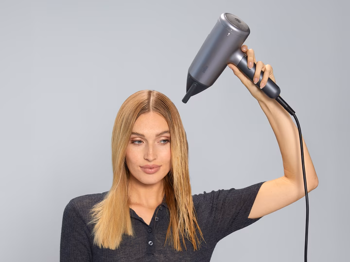 Woman using Braun HD 4.3 Hairdryer to style sleek, smooth hair.
