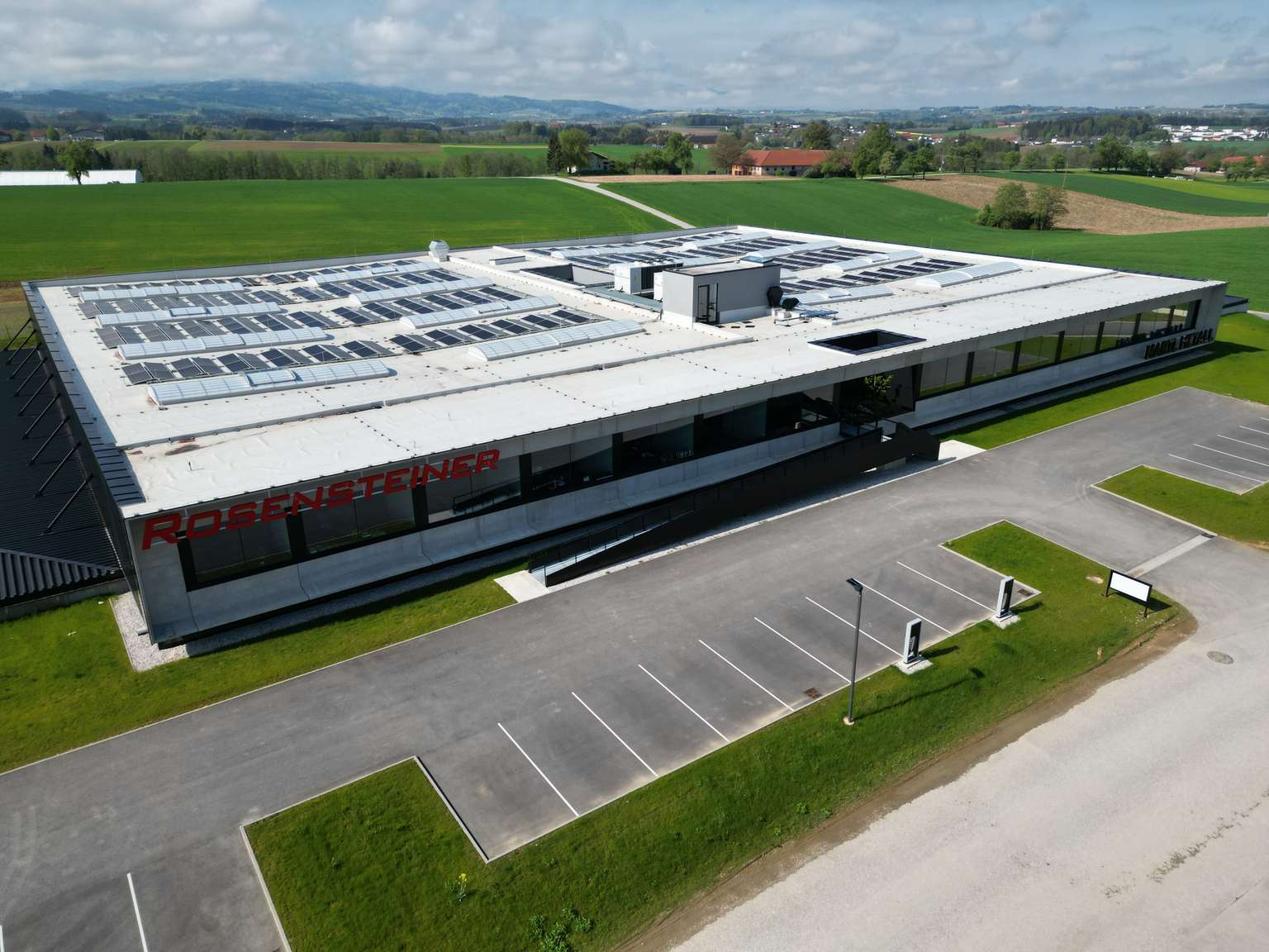 Vogelperspektive des Firmengebäudes Rosensteiner mit Solarpanelen am Dach und Parkplätzen.