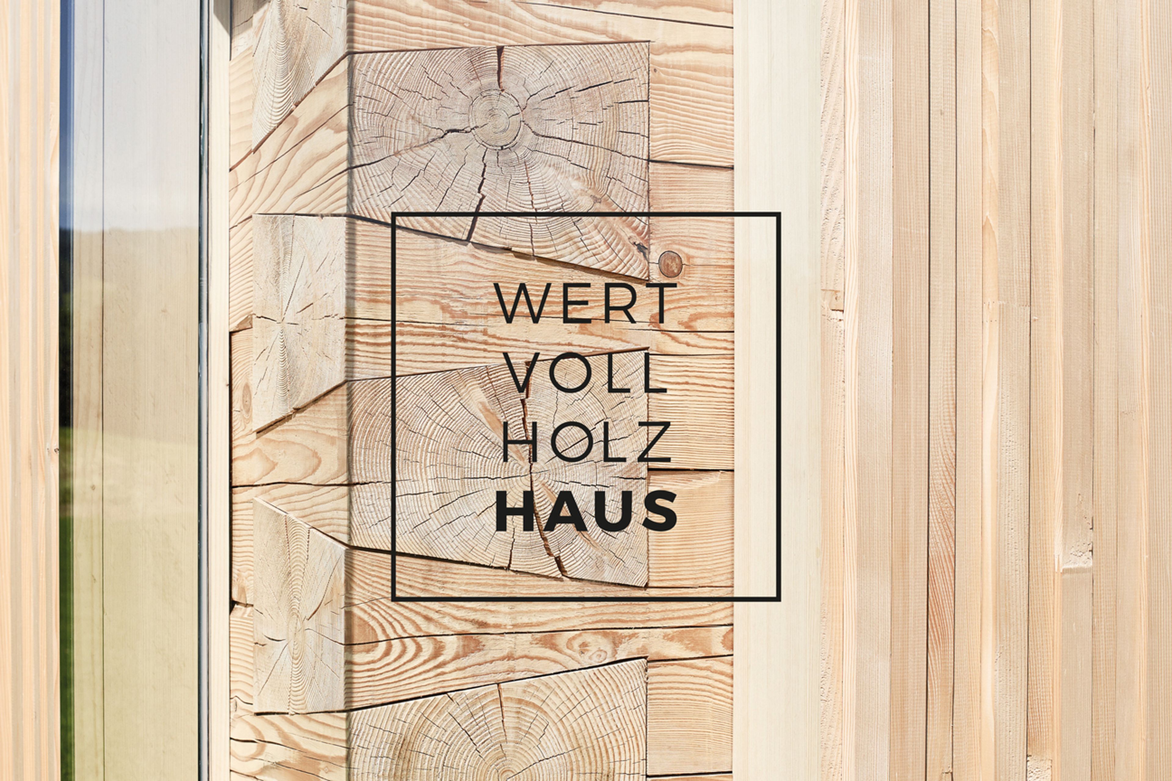Darstellung Detail Wertvollholzhaus – Massivholz Strickbauweise – mit Logo im Vordergrund