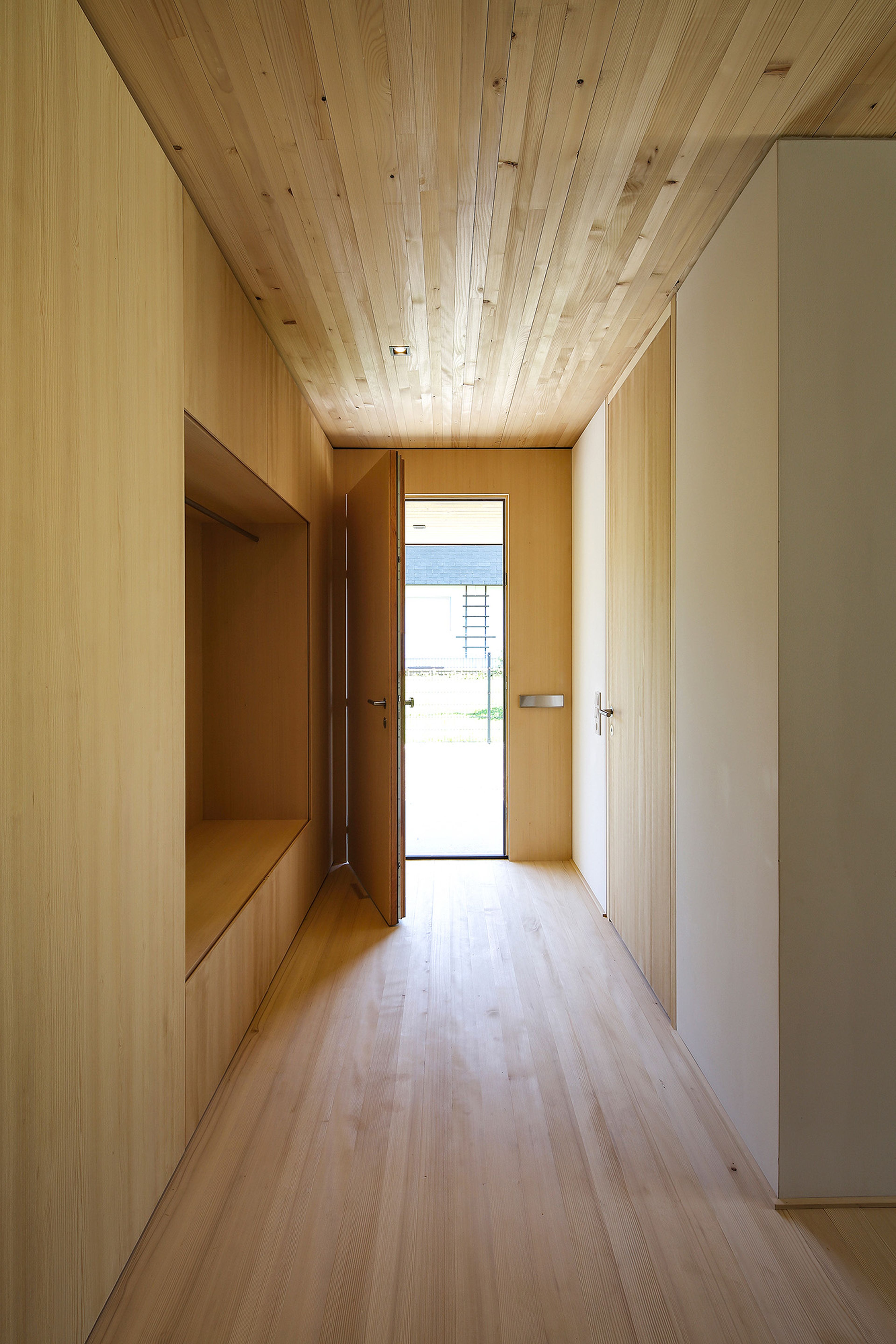 Innenansicht eines Holzhauses mit Holzdecke, Parkettboden und Garderobe in Holz