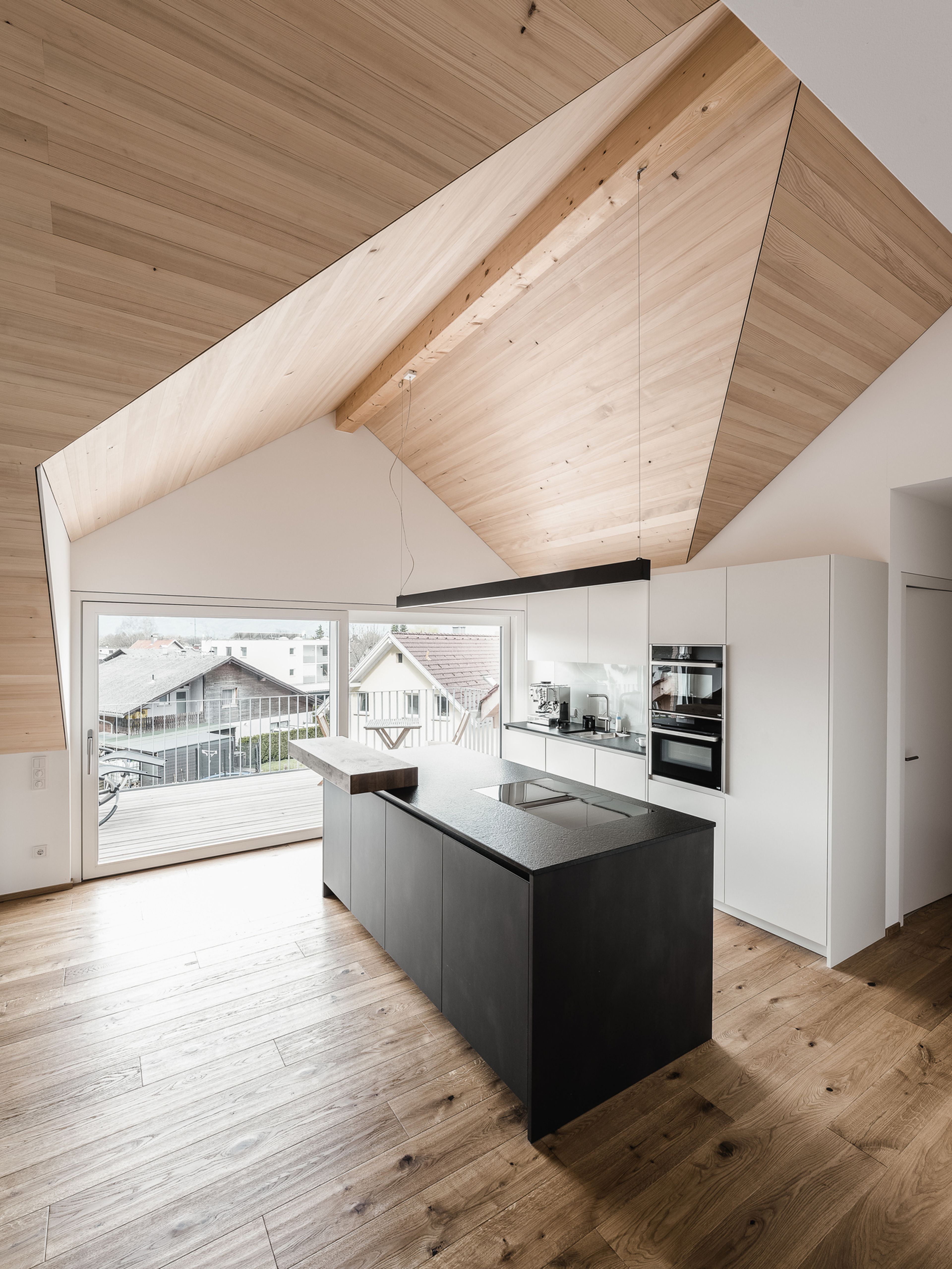 Innenausbau einer Sanierung mit Holzdecke und Parkettboden mit moderner Küche.