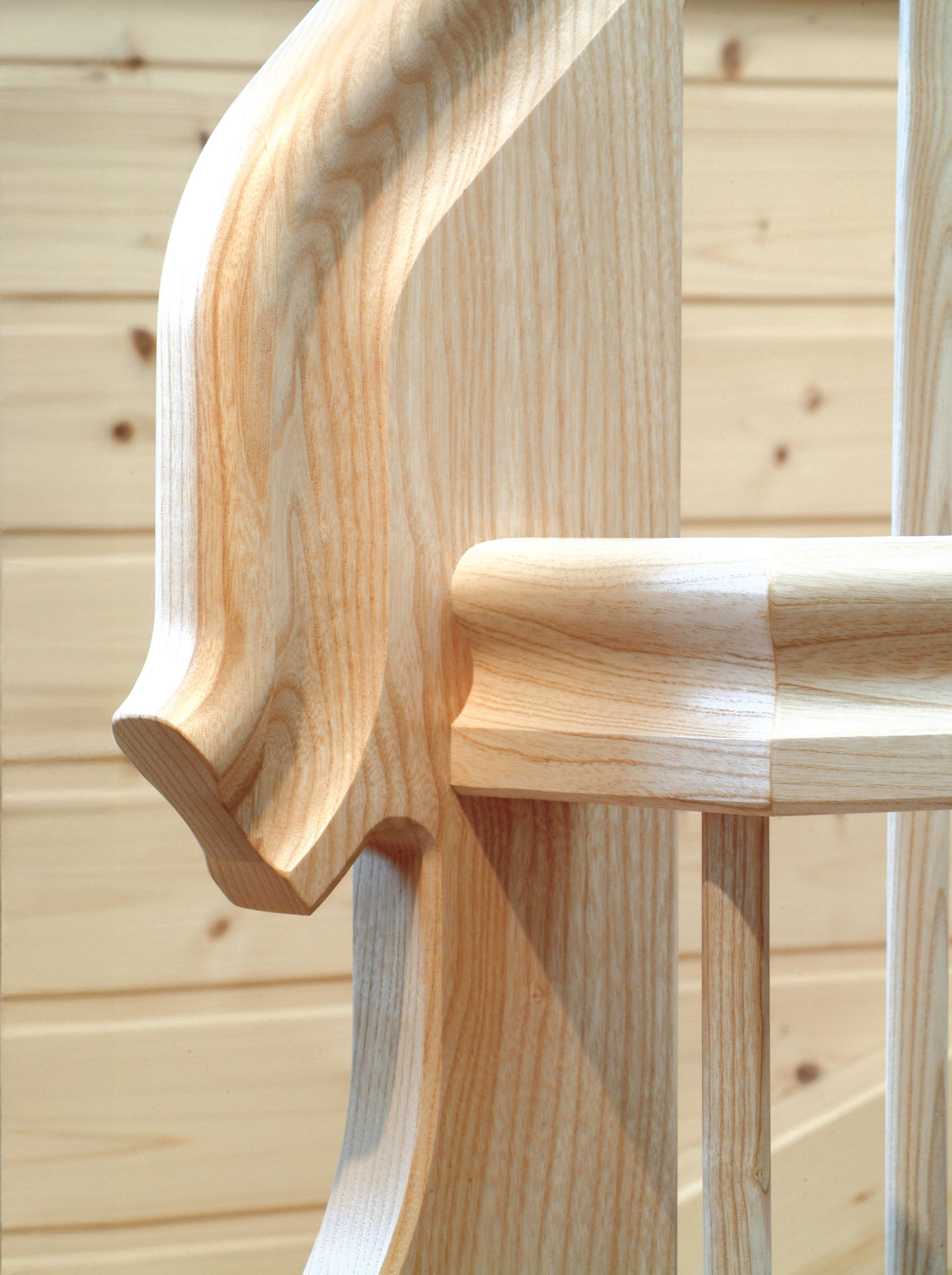 Nahaufnahme einer hölzernen Wendeltreppe mit glatten, polierten Kurven und einer hellen, natürlichen Oberfläche vor einer holzgetäfelten Wand.