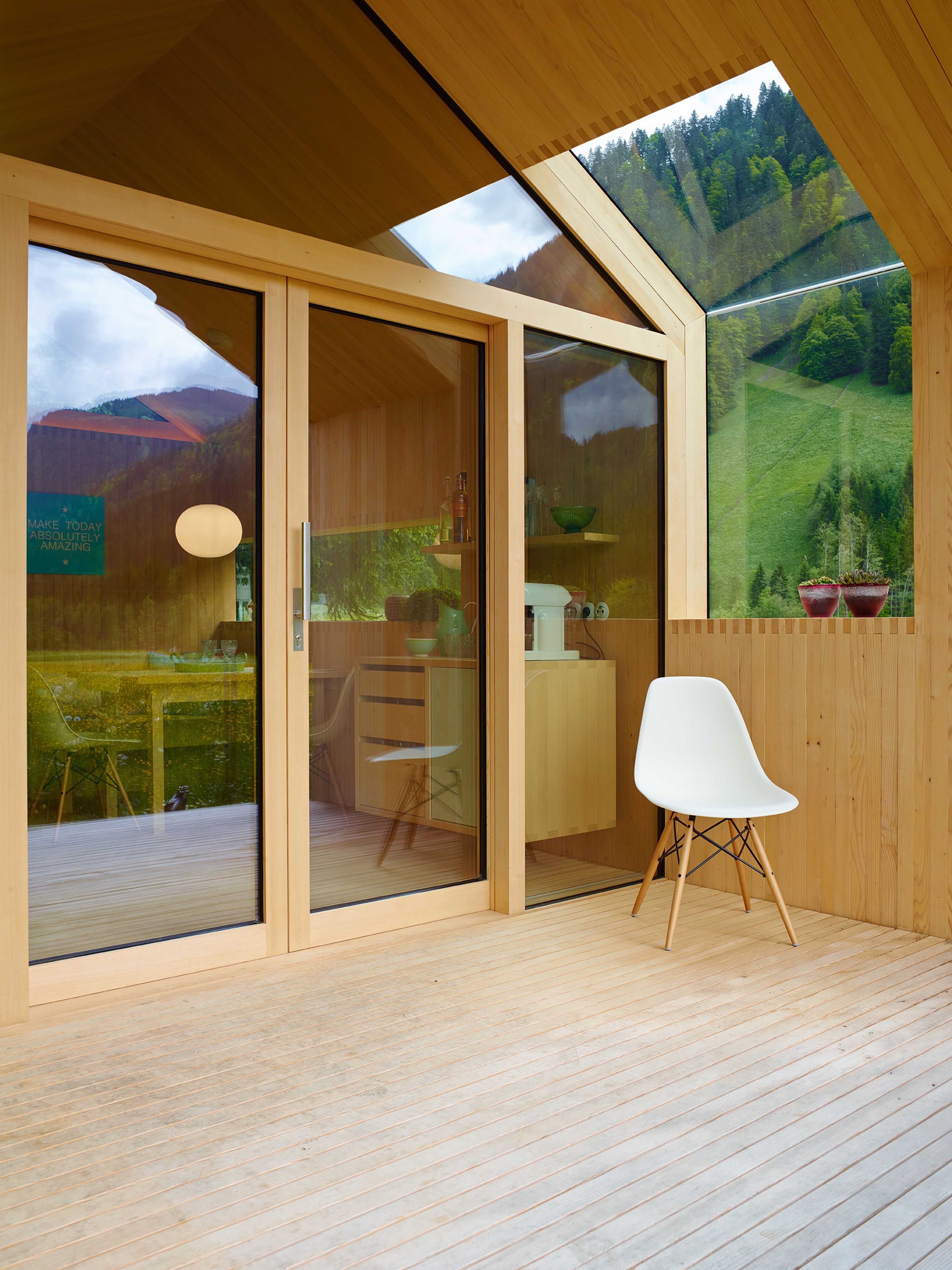 Kleines, modernes Gartenhaus in Holzbauweise mit Schindelfassade, klarer Formensprache und großem Fenster, umgeben von Grün.