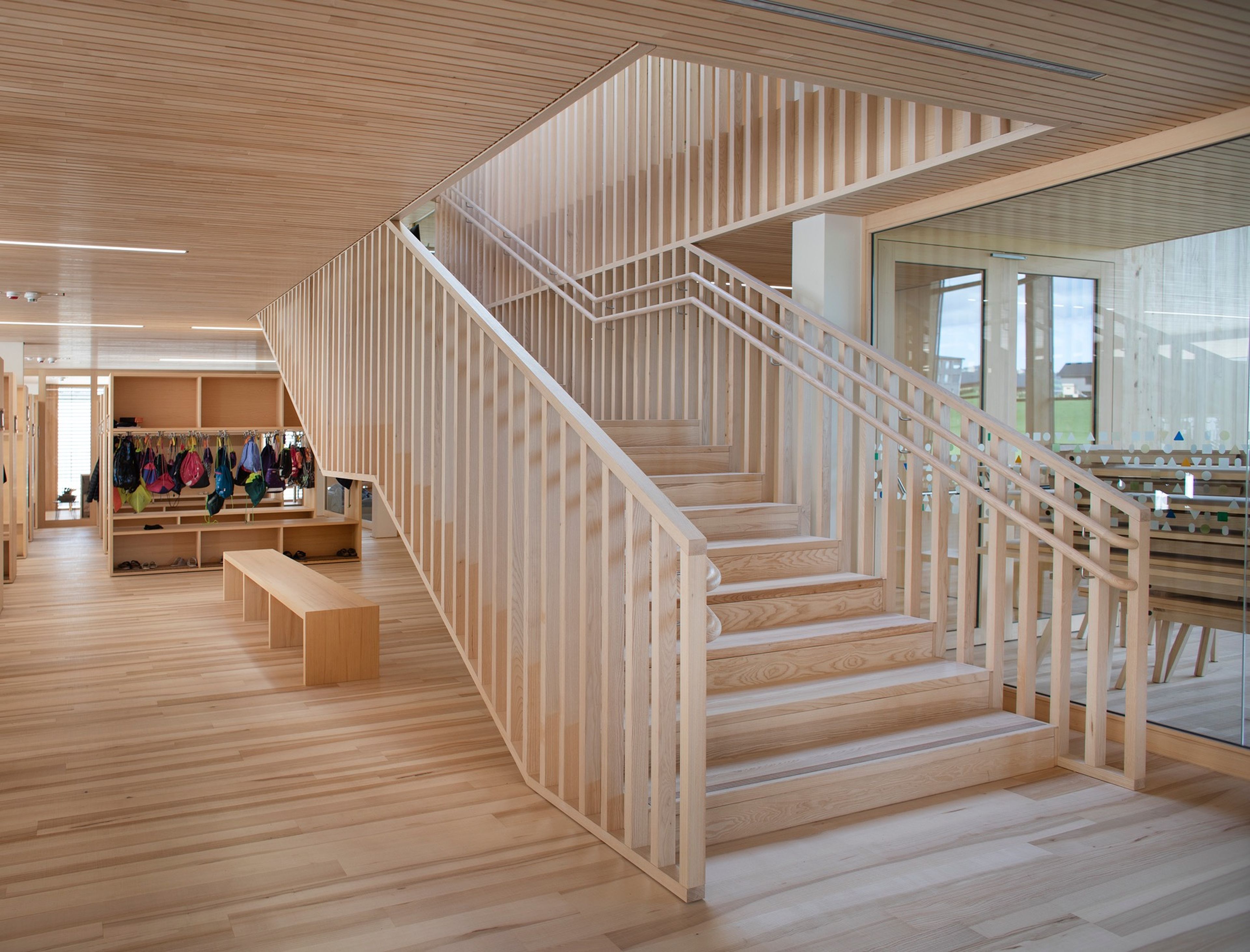 Eine Holztreppe, eingebettet in einen hellen Innenraum einer Schule