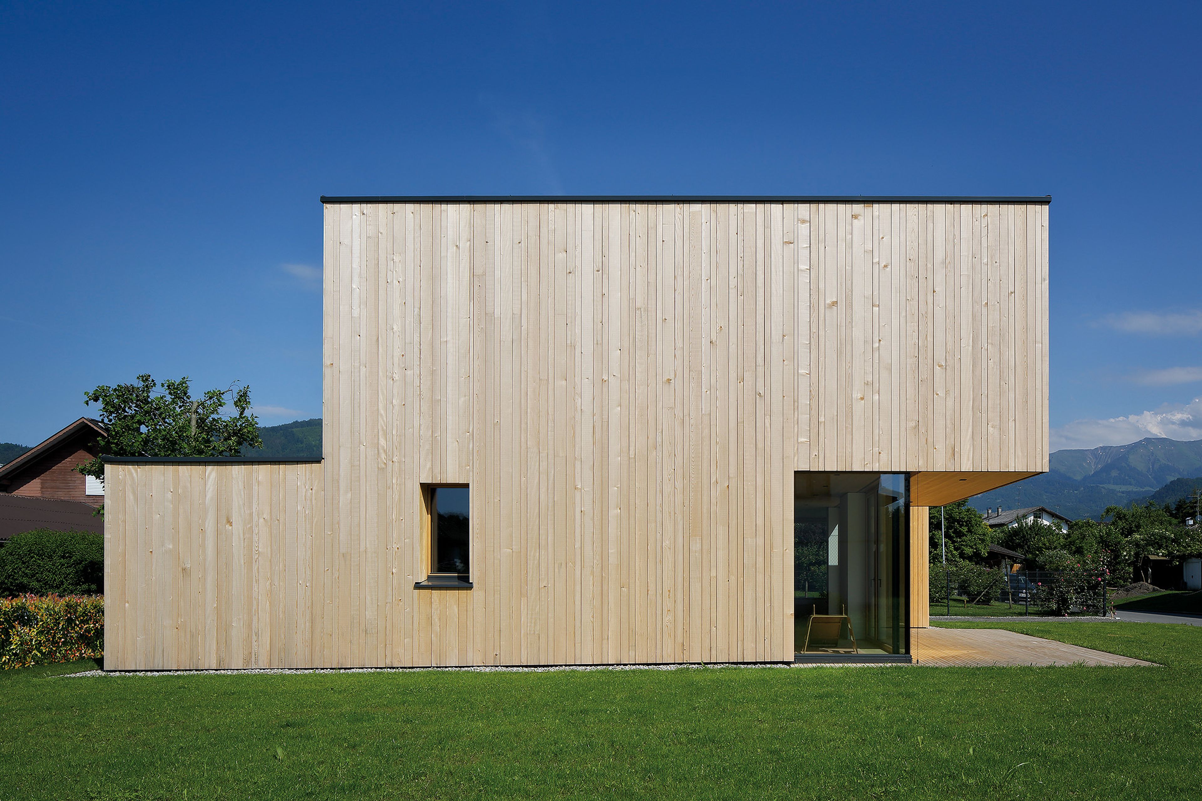 Außenansicht eines Holzhaus mit stehender Holzfassade und moderner, geradliniger Architektur
