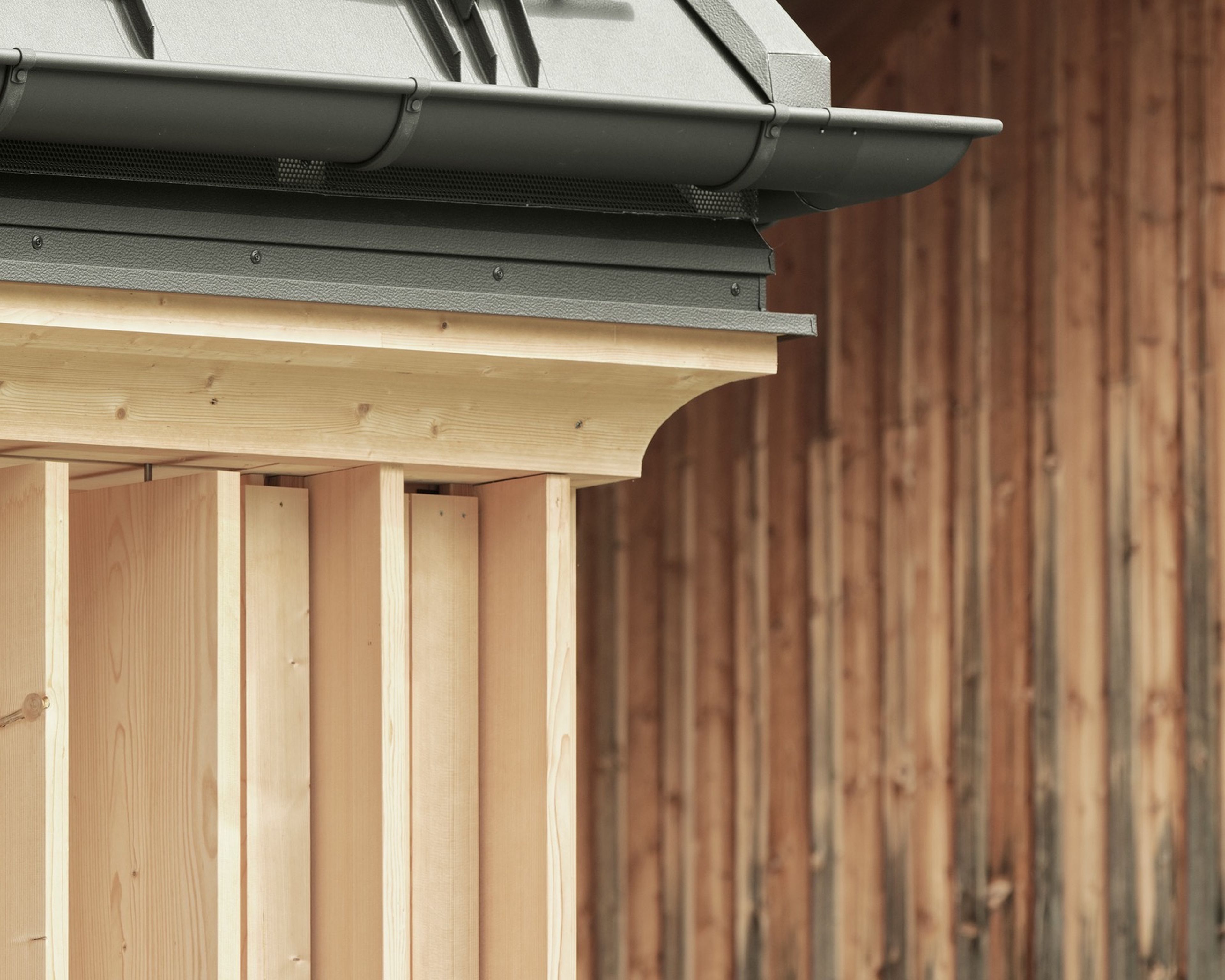Badehaus des Hotel Hirschen in Schwarzenberg: helles Holzgebäude mit dunklem Dach und Außenpool in einem Garten, Teil des Spa-Bereichs des Hotels.