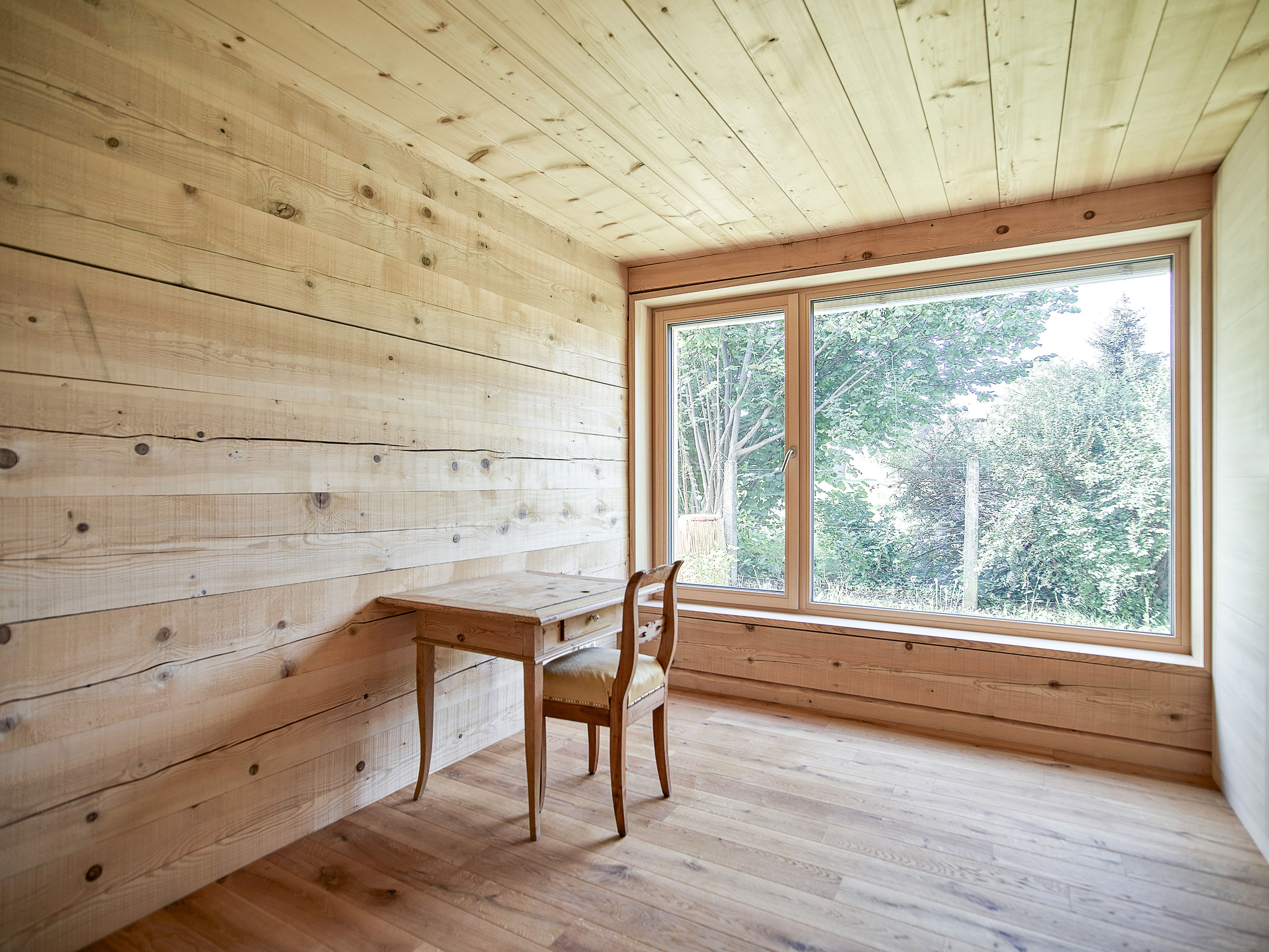 Innenansicht eines Wertvollholzhauses mit sichtbaren massiven Holzbalken, warmem Holzton und gemütlicher, natürlicher Atmosphäre.
