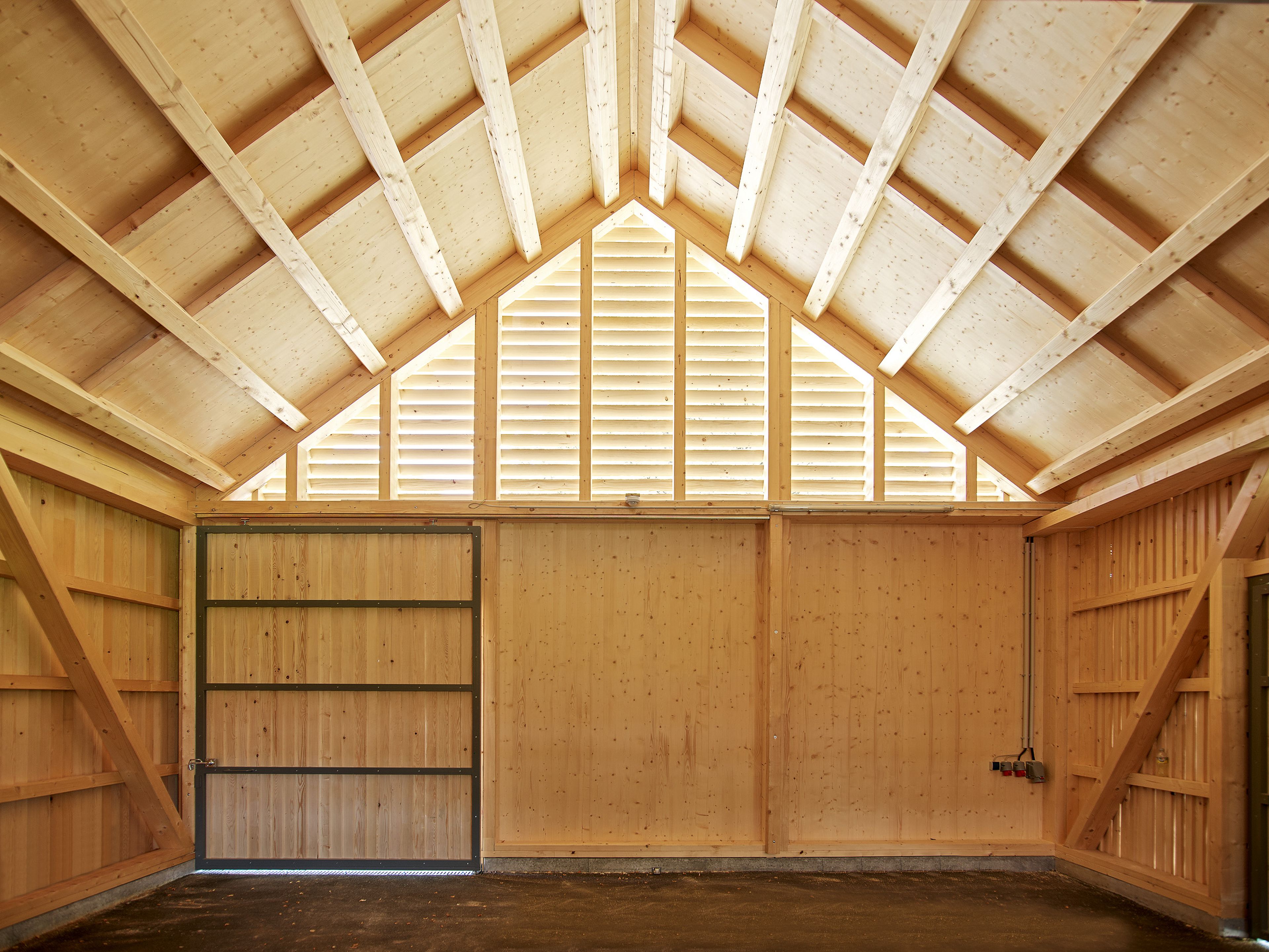 Innenansicht der Gerätehalle in der Birkenwiese Dornbirn, traditionelle Zimmermannsarbeit mit Holzdachstuhl.