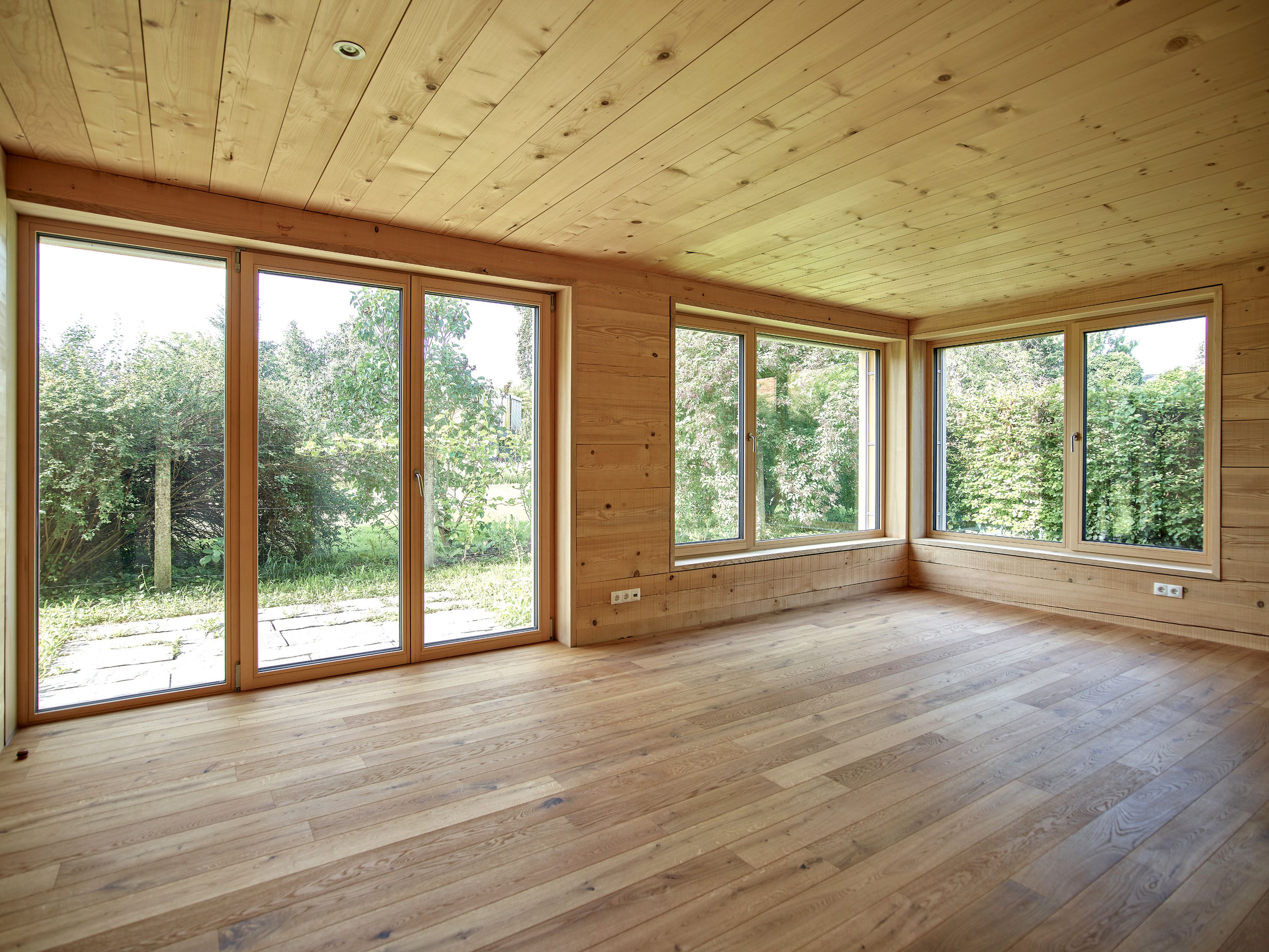 Innenansicht eines Wertvollholzhauses mit sichtbaren massiven Holzbalken, warmem Holzton und gemütlicher, natürlicher Atmosphäre.