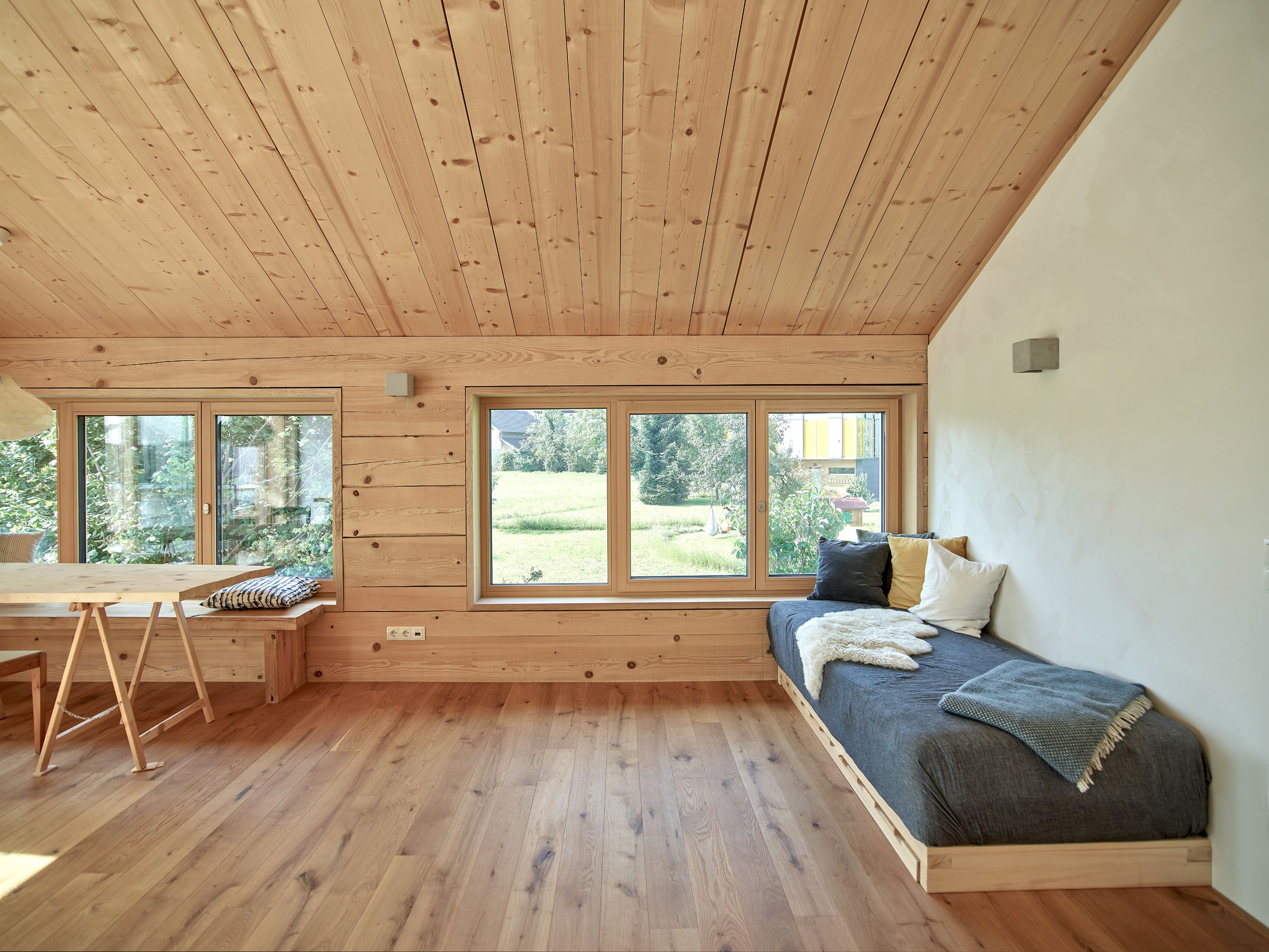 Innenansicht eines Wertvollholzhauses mit sichtbaren massiven Holzbalken, warmem Holzton und gemütlicher, natürlicher Atmosphäre.