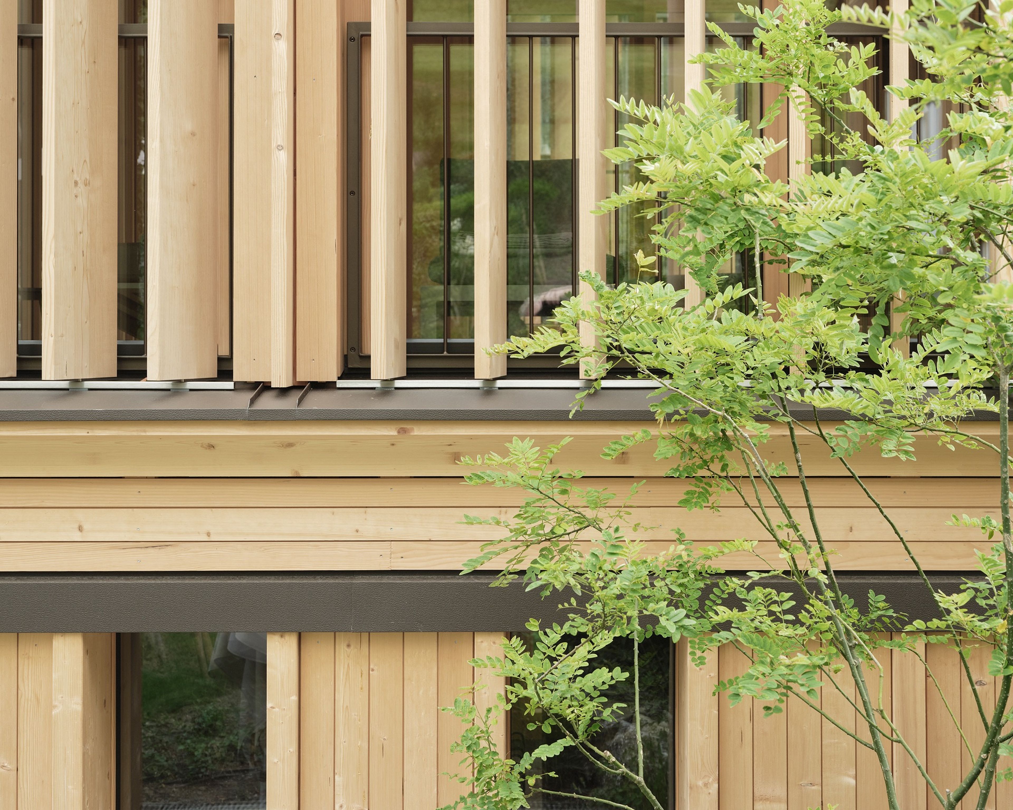 Badehaus des Hotel Hirschen in Schwarzenberg: helles Holzgebäude mit dunklem Dach und Außenpool in einem Garten, Teil des Spa-Bereichs des Hotels.