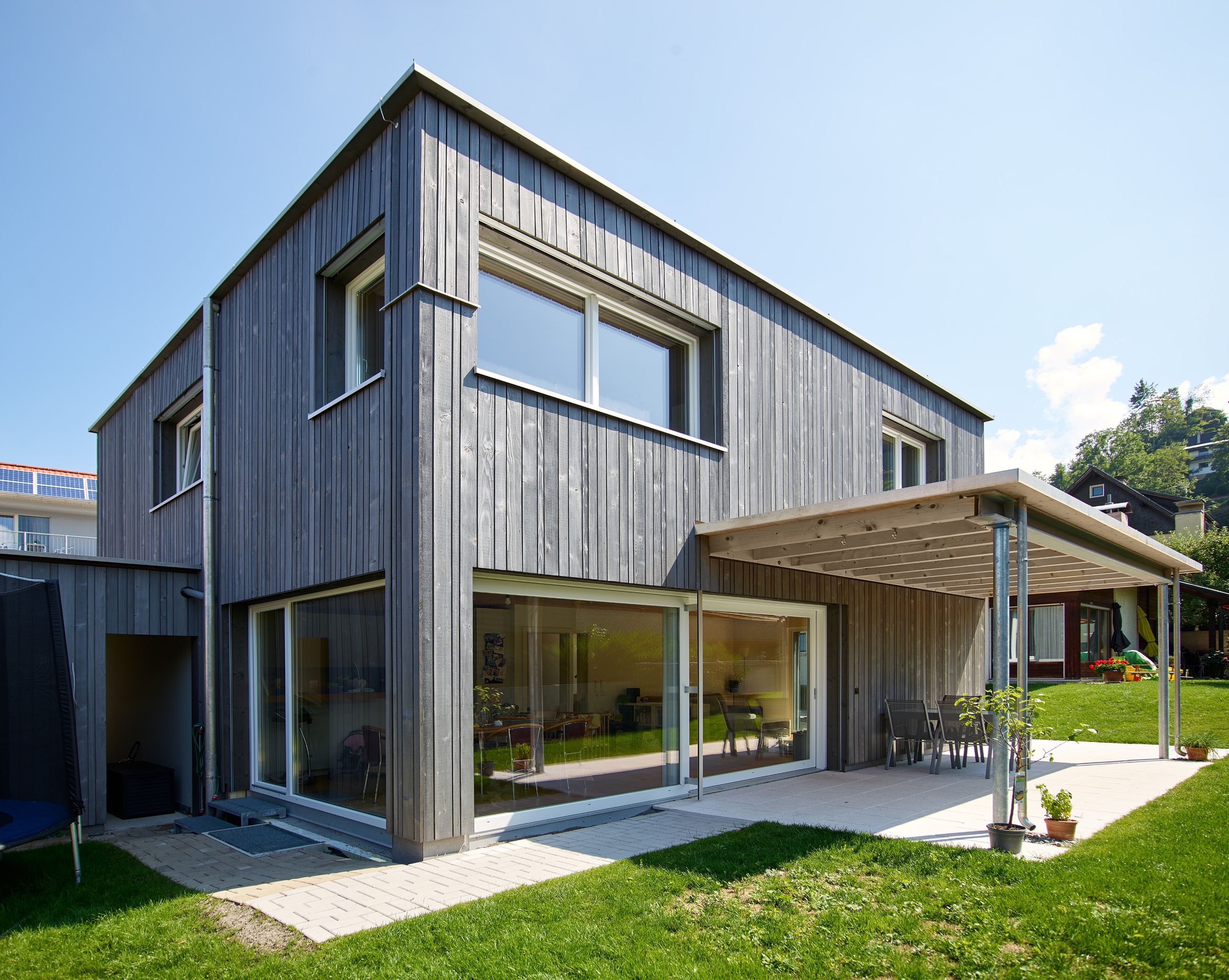 Außenansicht eines modernen, kleinen Holzhauses mit grauer Holzfassade