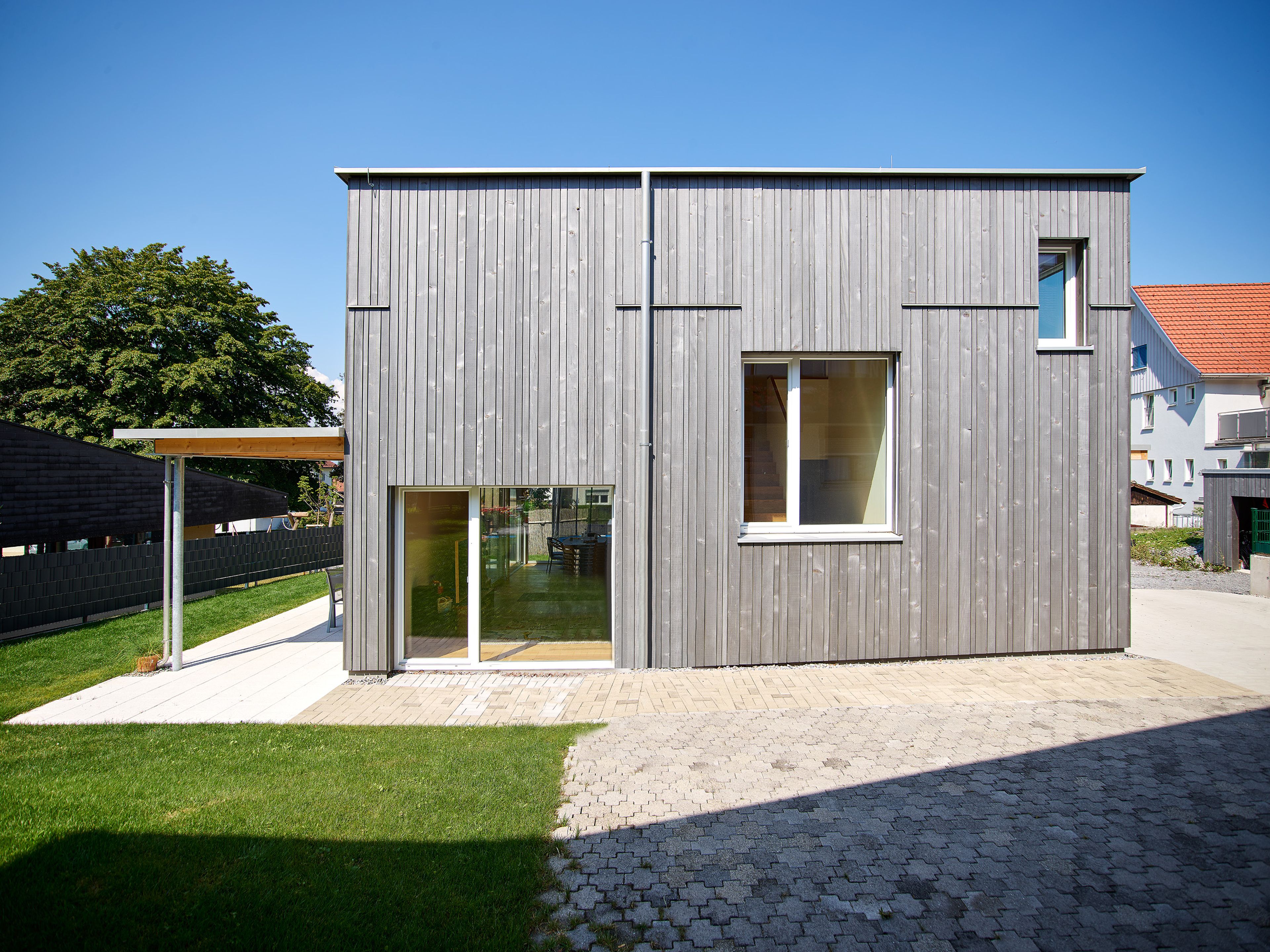 Außenansicht eines modernen, kleinen Holzhauses mit grauer Holzfassade