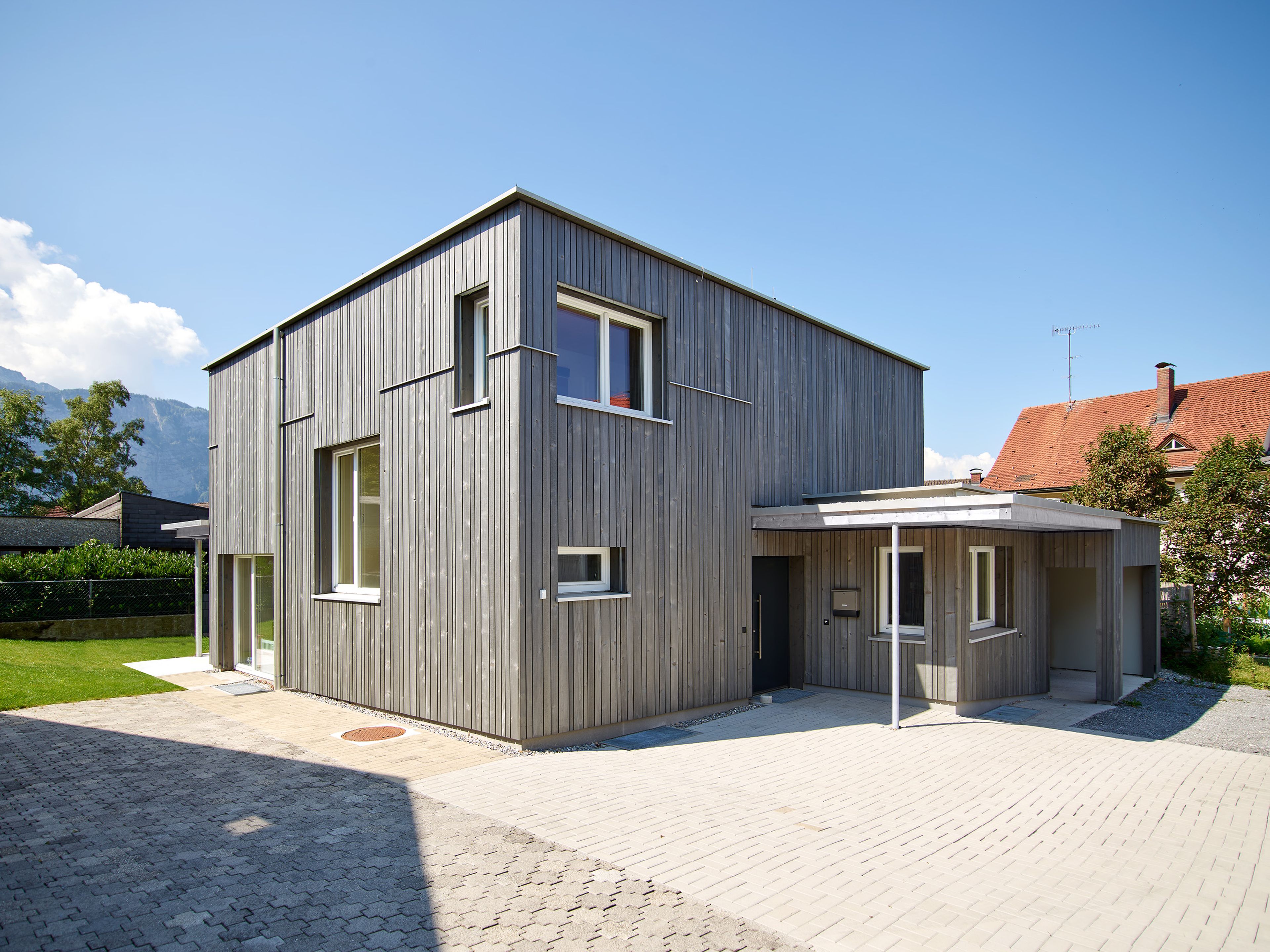 Außenansicht eines modernen, kleinen Holzhauses mit grauer Holzfassade