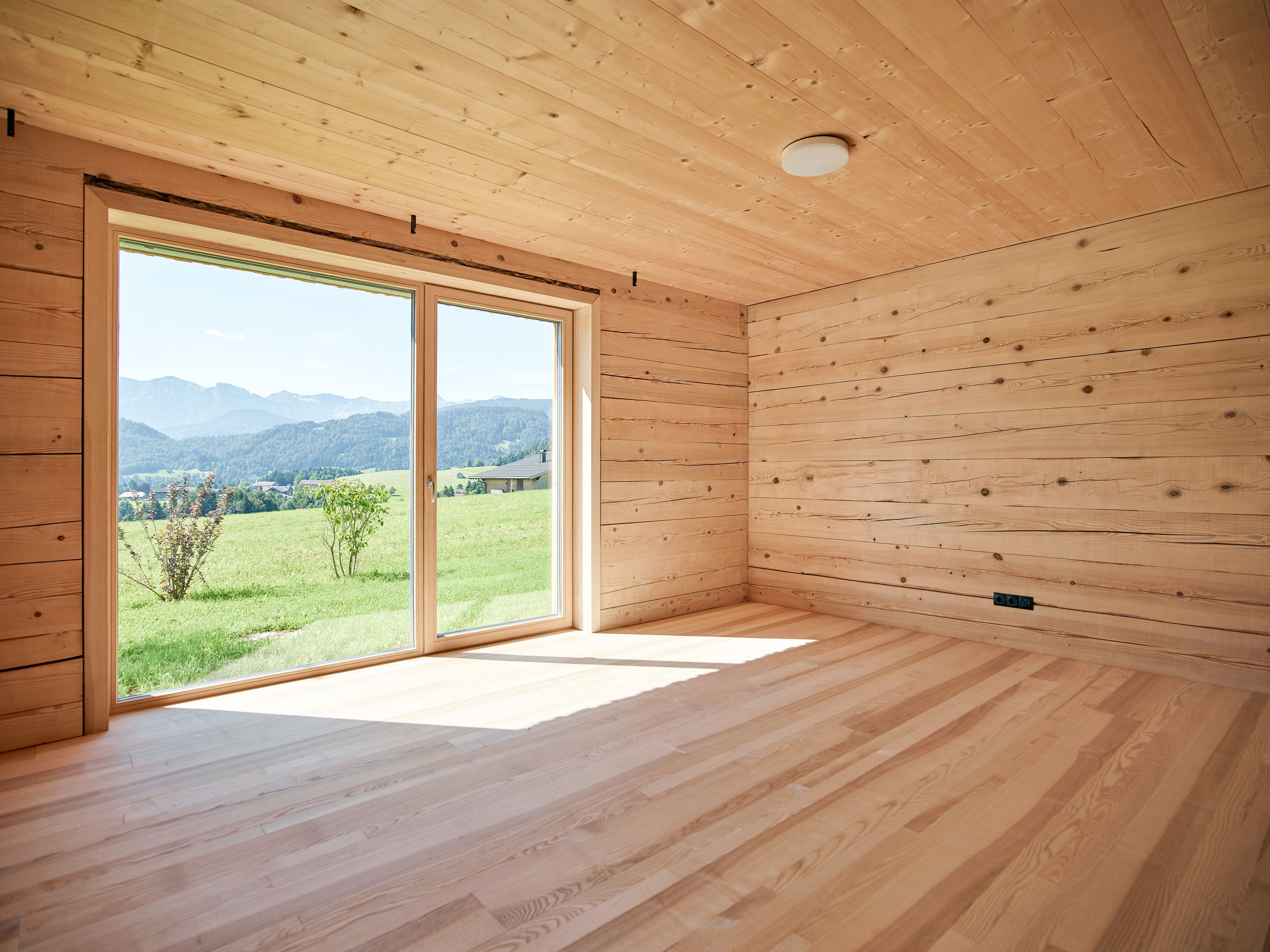 Innenansicht eines Wertvollholzhauses mit sichtbaren massiven Holzbalken, warmem Holzton und gemütlicher, natürlicher Atmosphäre.