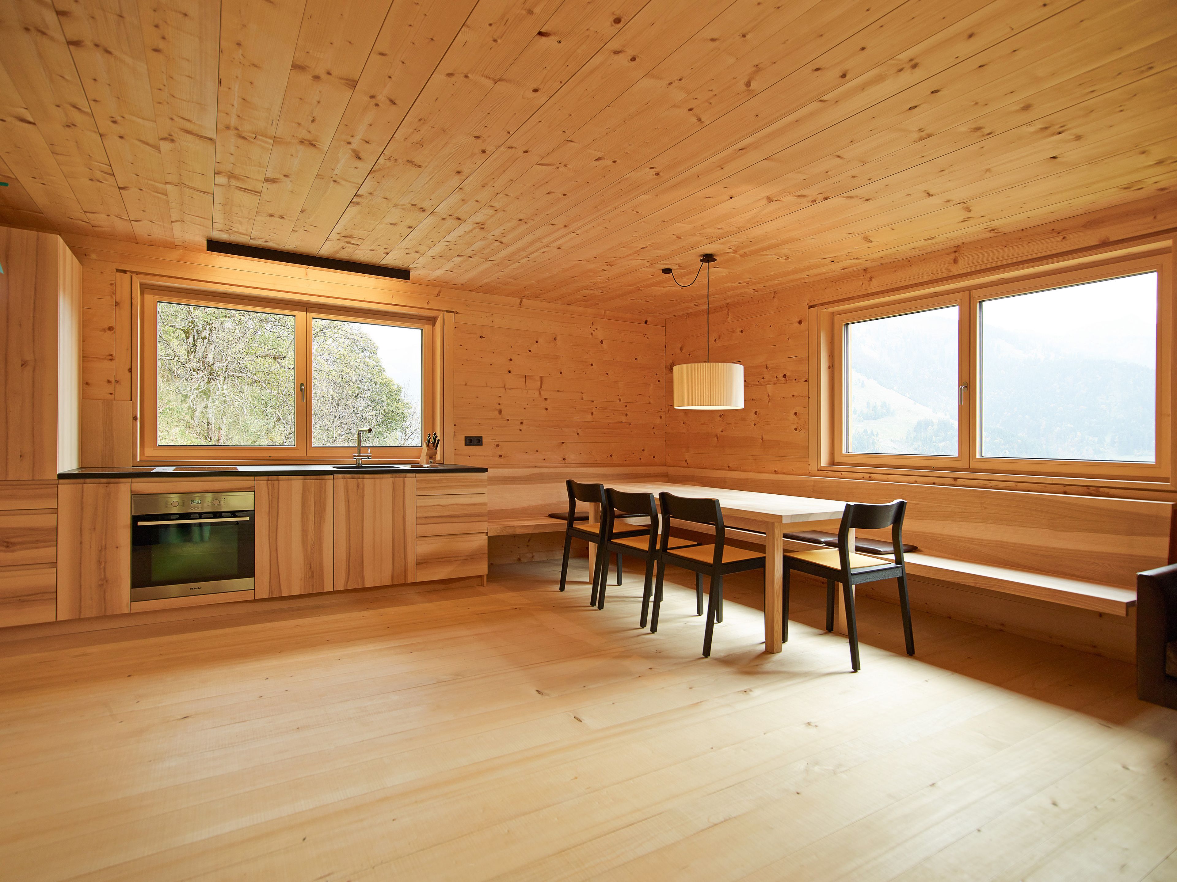 Innenaufnahme eines Einfamilienhauses in Holz – in Strickbauweise. Gemütlicher Raum mit Holzdecke, Holzboden und Kaminofen.