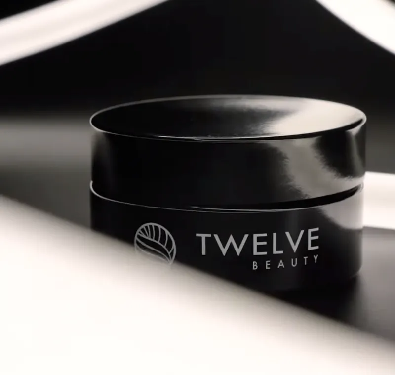 Close-up of a glossy Miron cosmetic jar featuring the TWELVE BEAUTY logo and circular emblem on a dark, reflective surface.