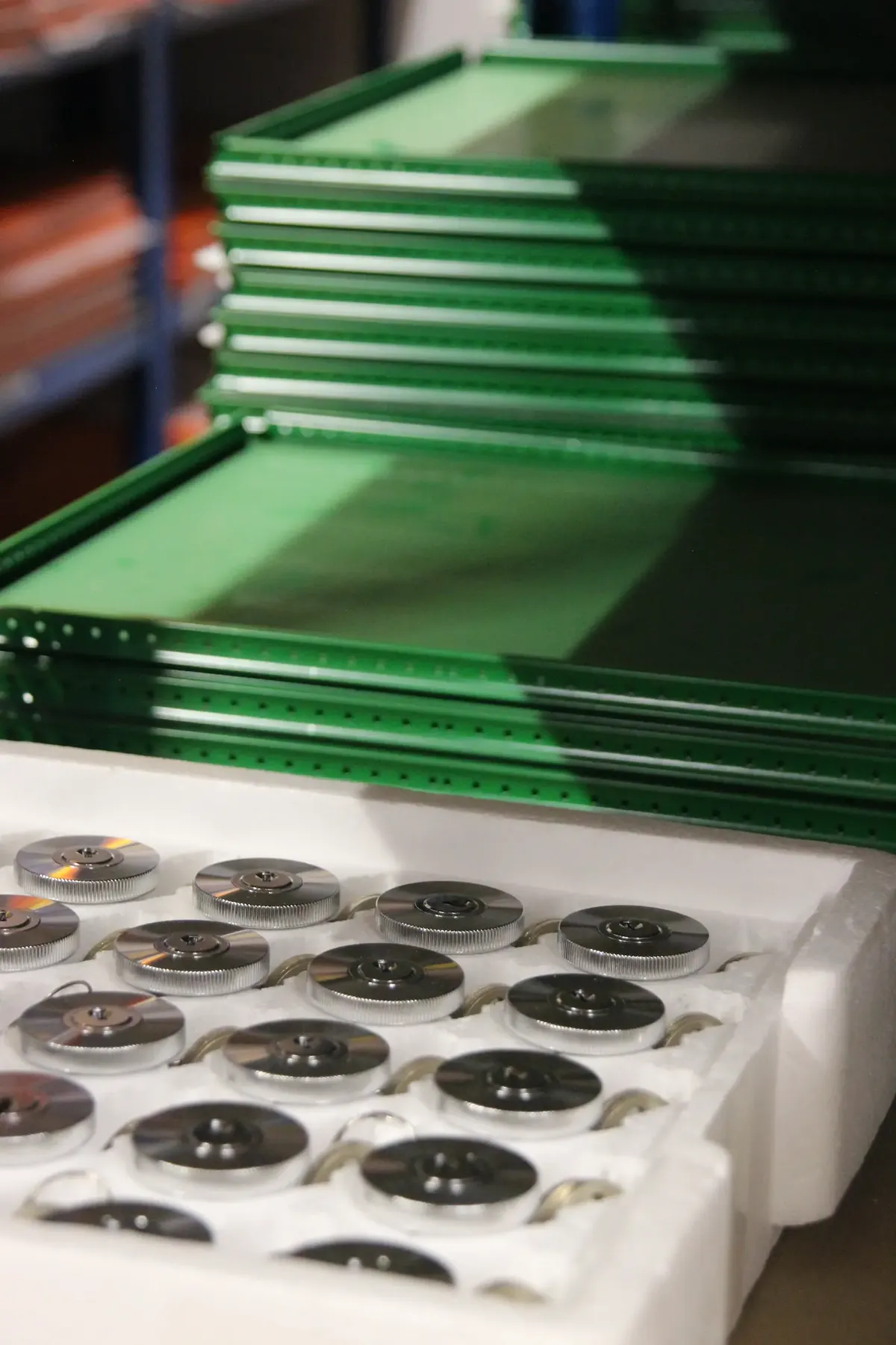 Grüne USM Haller Tablare und dazugehörige Schlösser im Lager gestapelt.