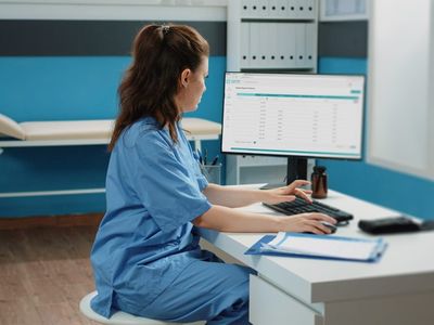 Woman working as nurse with computer and documents in cabinet, checking files for examination appointment. Medical assistant looking at screen for patient information and checkup visit
