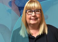 Smiling woman with glasses and blonde hair wearing a dark shirt, with medical-themed background elements.