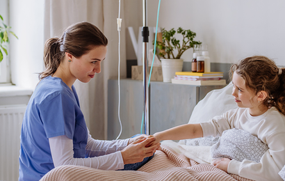 Healthcare professional providing home infusion treatment and support to a child in a bedroom setting.