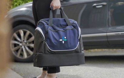 Nurse standing at home door with HealthNet Nurse Visit Bag