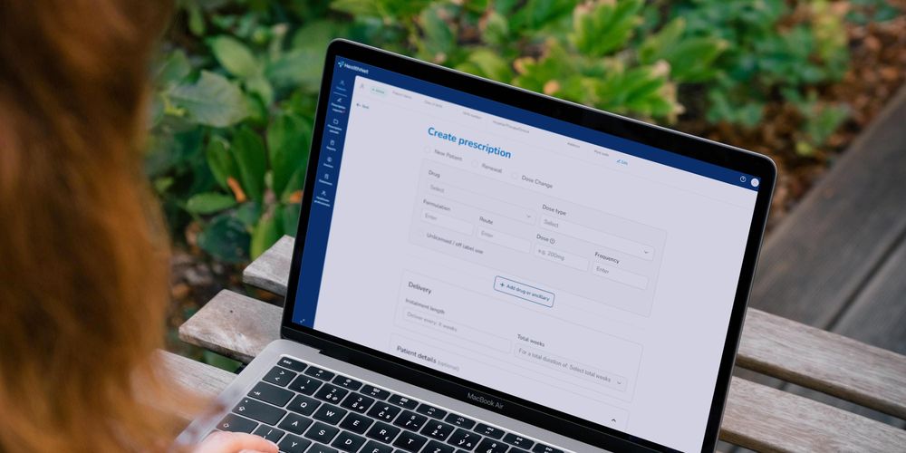 Person using a laptop on an outdoor table, with the HealthNet Clinician Gateway interface open displaying a “Create prescription” form.