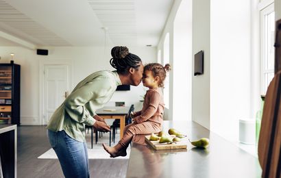 A woman gently kisses a young child on the forehead.