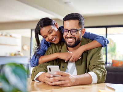 Woman hugging a smiling man from behind.