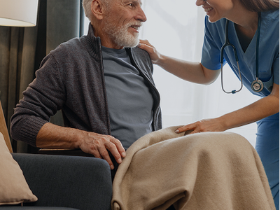 Nurse smiling at an elderly man in a wheelchair.