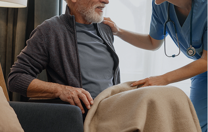 Elderly man in a wheelchair smiling at a nurse.