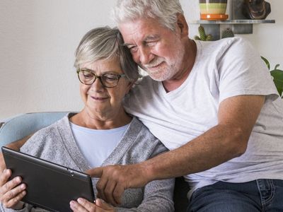 couple of seniors smiling looking at digital screen
