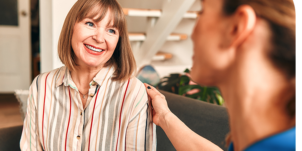 Nurse giving a supporting conversation with a patient in a striped shirt.