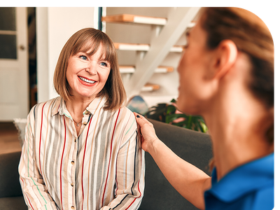 Two women talking and smiling in a living room.