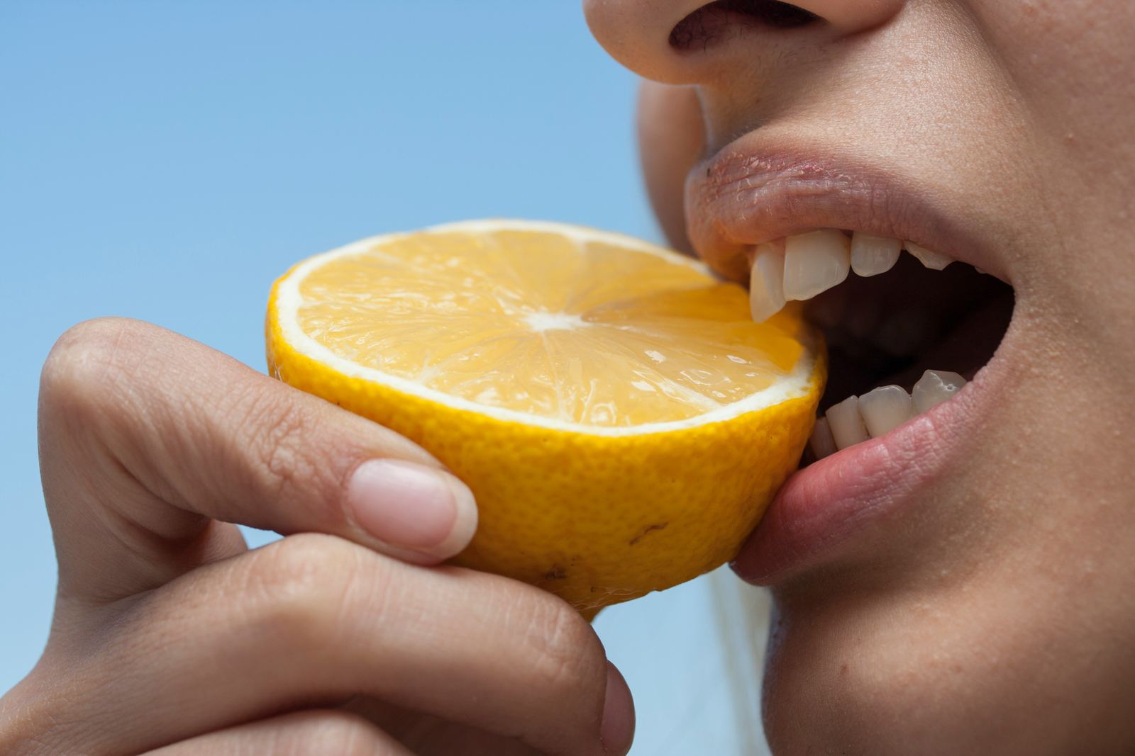 Someone tasting a slice of lemon