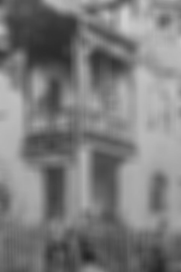 Vintage photo of people on a balcony and two men with bicycles in front of a building with a sign reading "Bureau des Elektrizitätswerks."