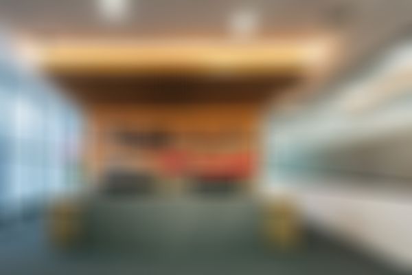 Innenaufnahme des umgebauten Kundencenters in Reutte mit zentralem Empfangstresen aus Holz- und Steinelementen. Dahinter befindet sich eine beleuchtete Wandgestaltung mit Bergsilhouette und EWR-Logo. Große Fenster und eine Glaswand rahmen den Empfangsbereich ein.