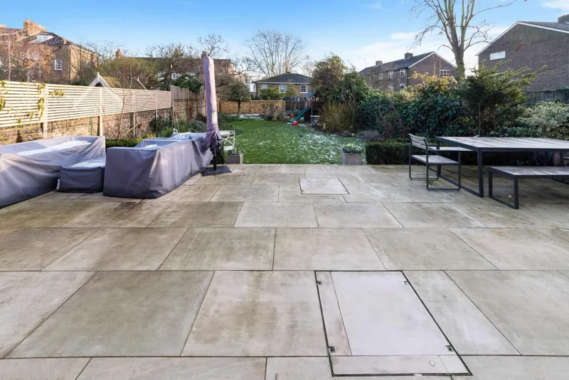 Stone paved terrace with garden furniture and lawn beyond