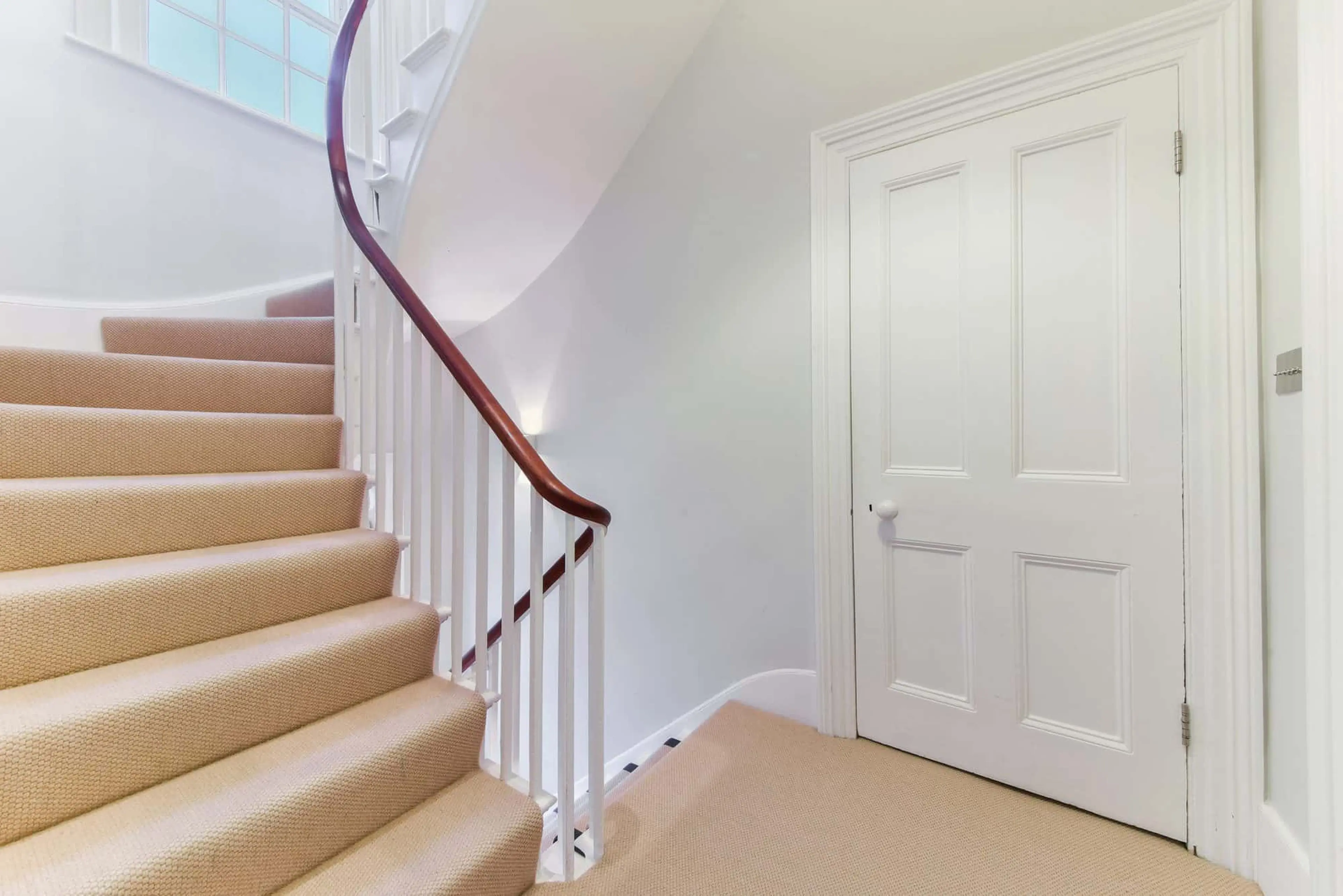 Curved staircase and landing with cream carpet