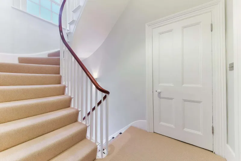 Curved staircase and landing with cream carpet