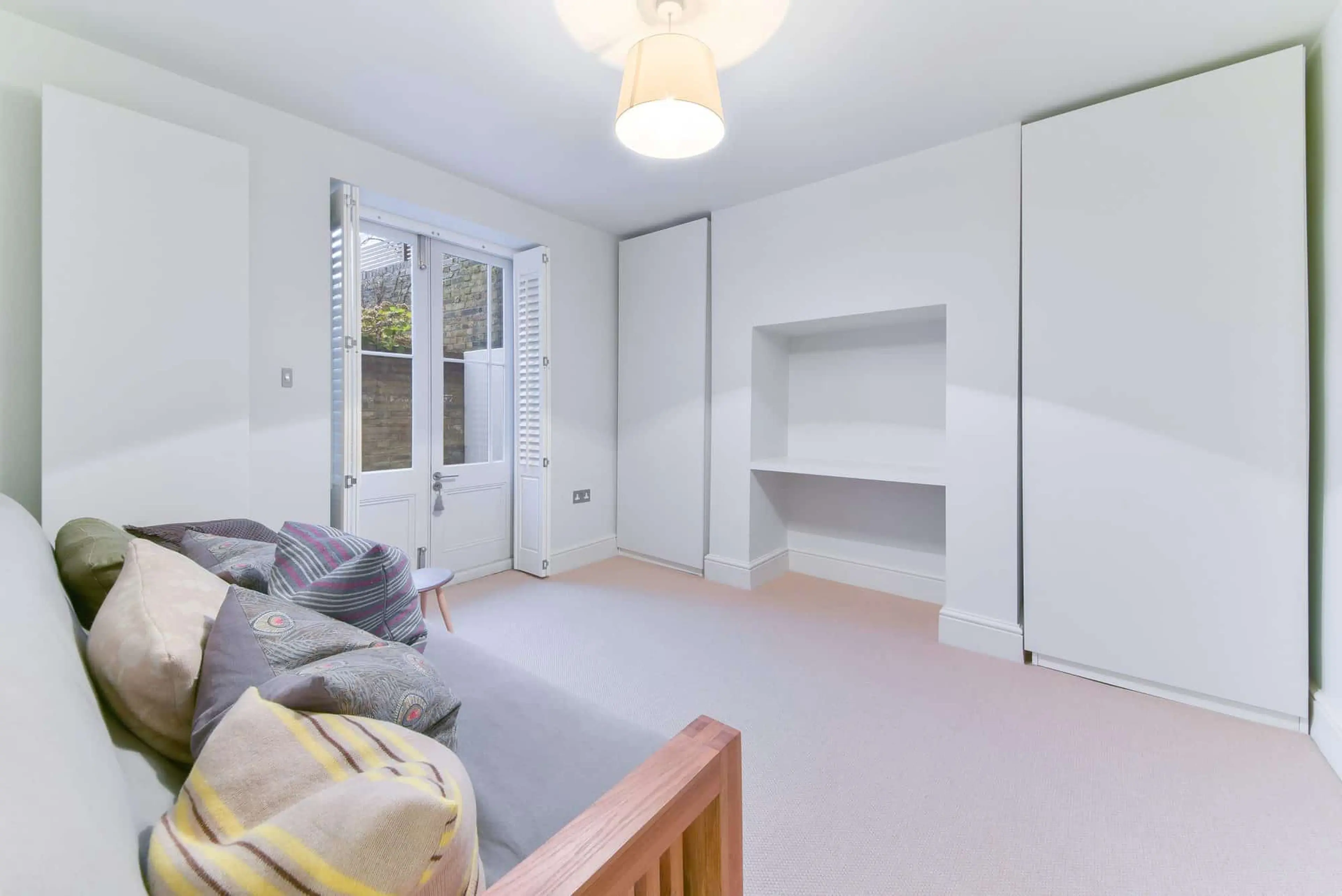Lower-ground bedroom with fitted wardrobes and doors to the courtyard
