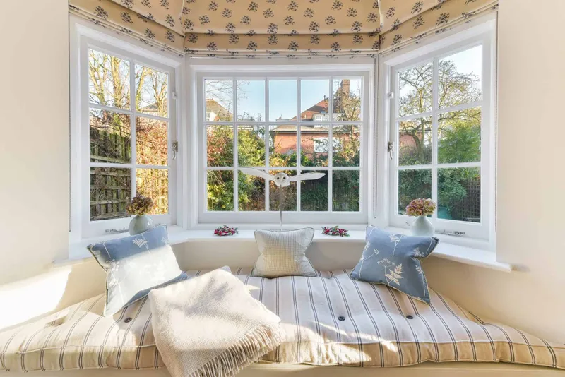 Bay window seat with fitted cushions and patterned blinds