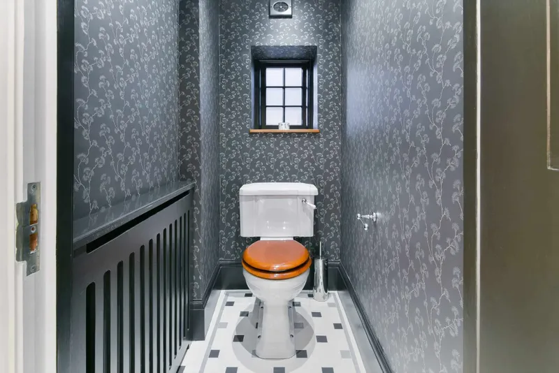 WC with hand-made patterned wallpaper and mosaic floor tiling