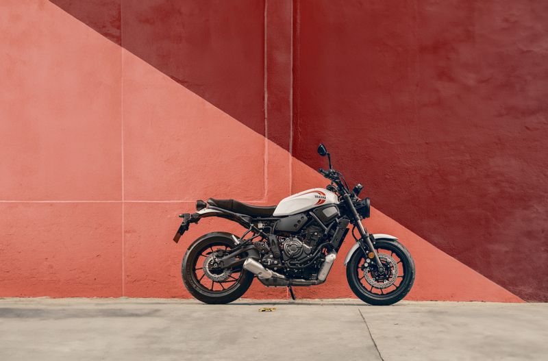 Een Yamaha XSR700 geparkeerd tegen een rood-roze geometrische muur